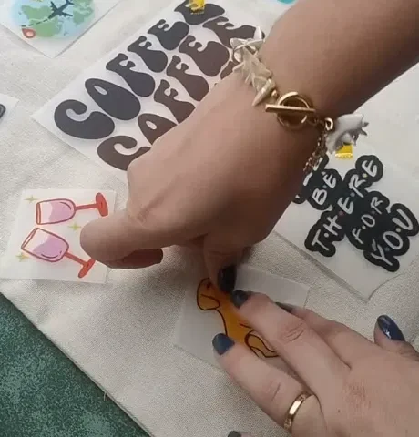 Mãos escolhendo e posicionando adesivos na ecobag